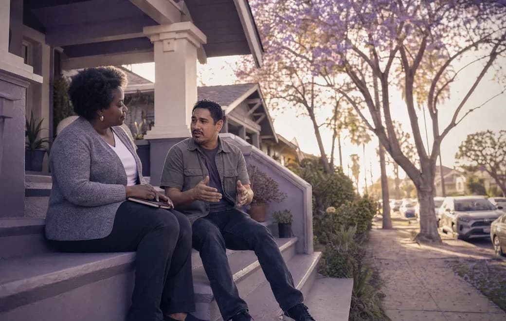A person and their care coordinator talking on a porch in an LA neighborhood